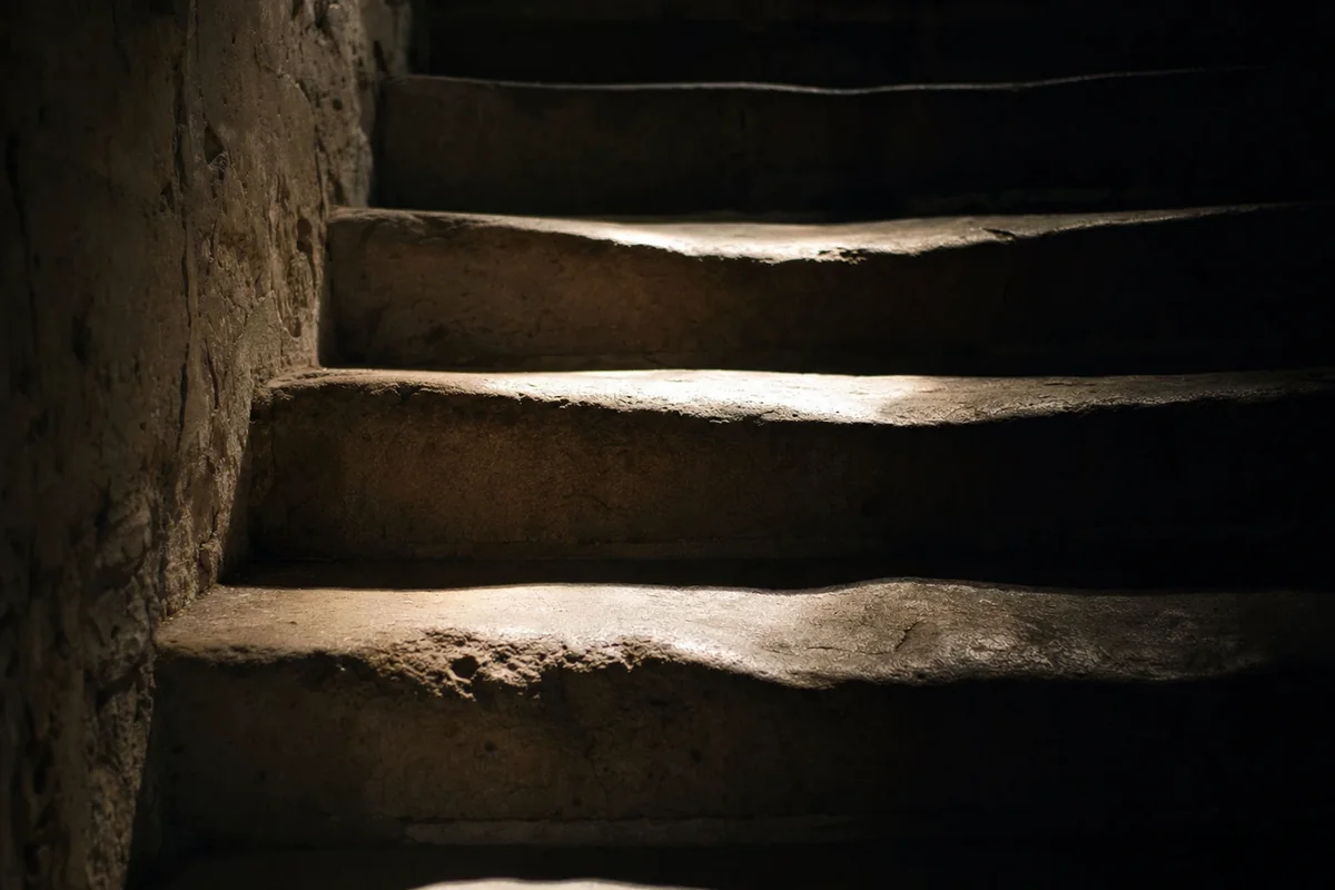 Stone steps worn into shallow hollows by a century of feet, lit by a single shaft of light